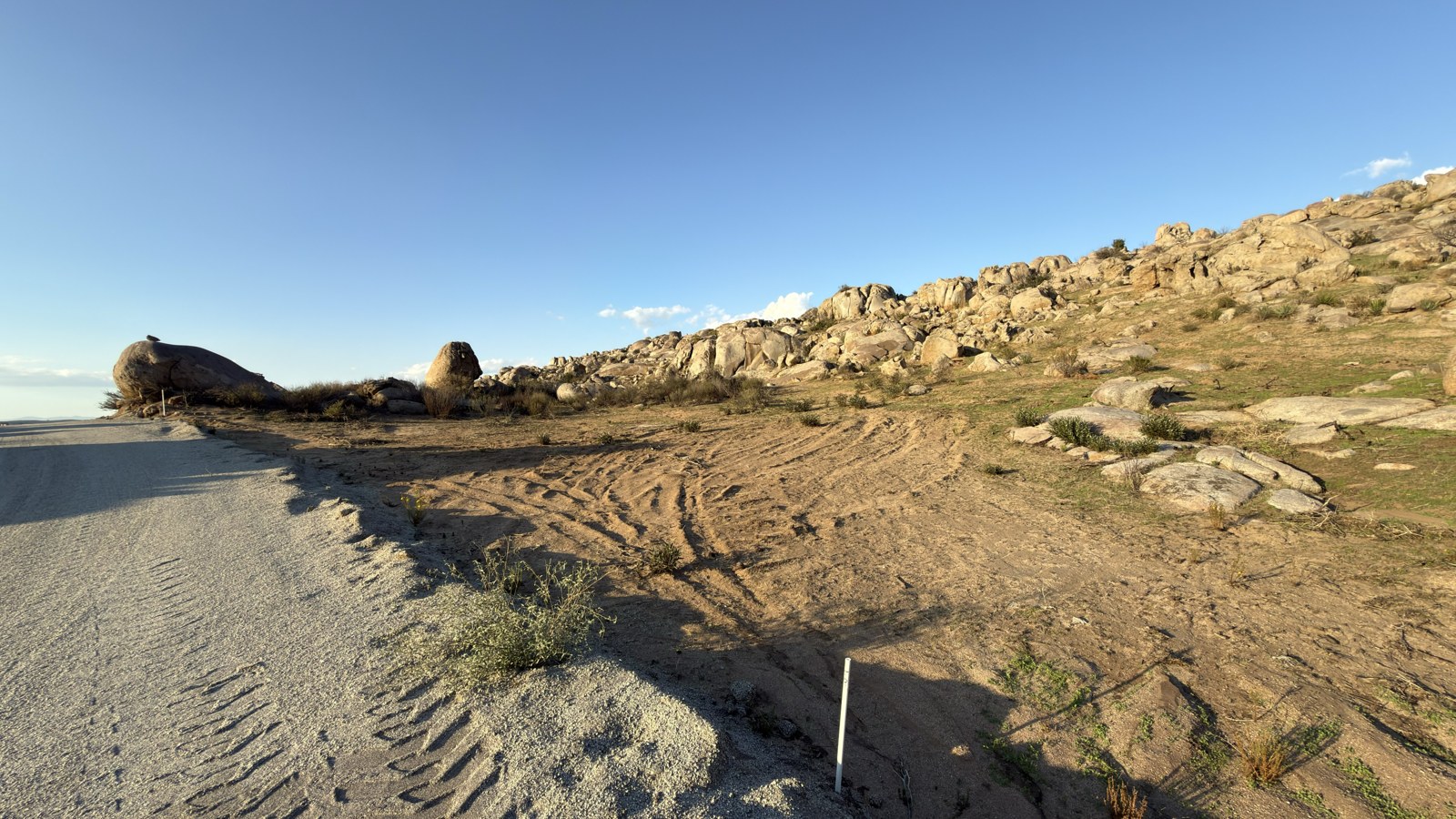 Vista desde el camino junto al lote 15, manzana 34, con terreno rocoso y montañas
